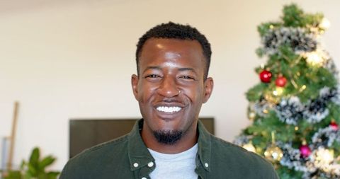 Smiling Man in Cozy Living Room with Decorated Christmas Tree