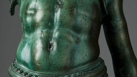 Verdigris bronze torso closeup showing patina texture, navel detail and ornate waist belt