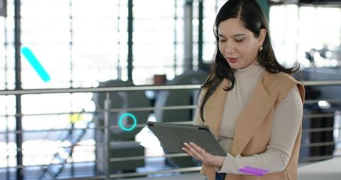 Professional woman holding tablet and checking data at modern coworking office railing