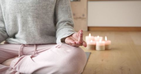Woman Meditating with Candles Promoting Relaxation and Mindfulness
