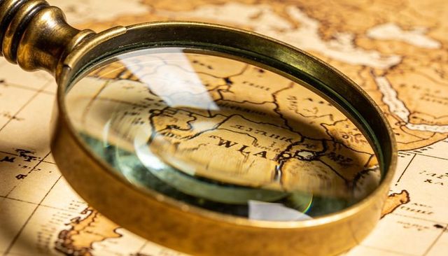 Brass magnifying glass focusing on vintage map details revealing antique cartography textures