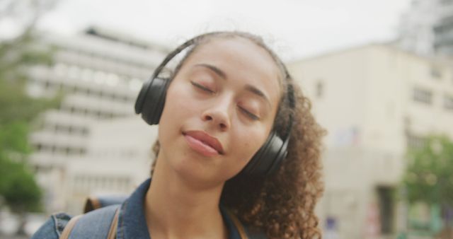 Happy biracial woman in city, wearing headphones and smiling - Download Free Stock Photos Pikwizard.com