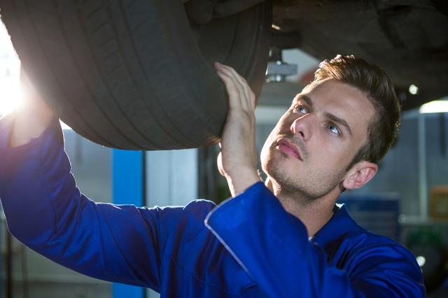 Mechanic examining car tyre at repair garage