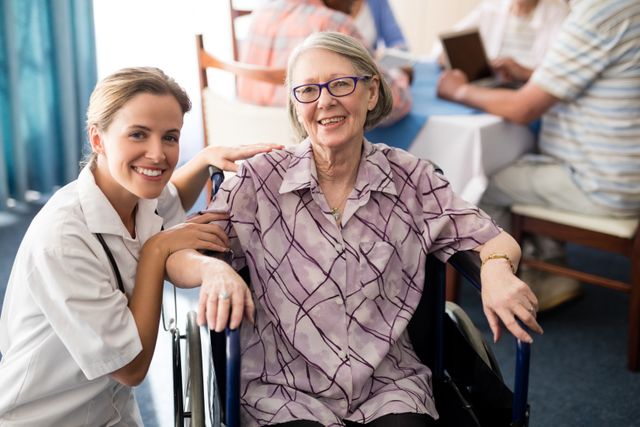 Portrait of smiling female doctor with disabled senior woman sitting on wheelchair at retirement home