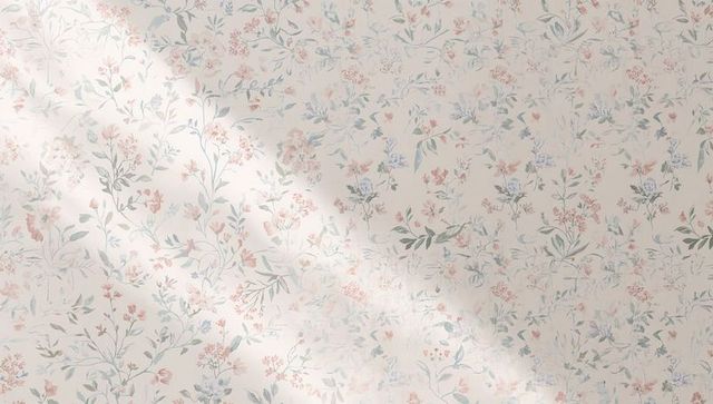 Soft pastel floral wallpaper on plaster wall catching diagonal sunbeam and texture