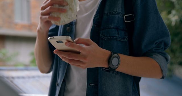 Young Man Using Smartphone while Eating Snack Outdoors - Download Free Stock Images Pikwizard.com