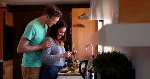Young Couple Preparing Salad Together in Cozy Kitchen