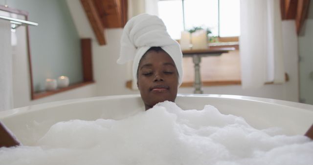 African american attractive woman relaxing in foam bath in bathroom. beauty, pampering, home spa and wellbeing concept.