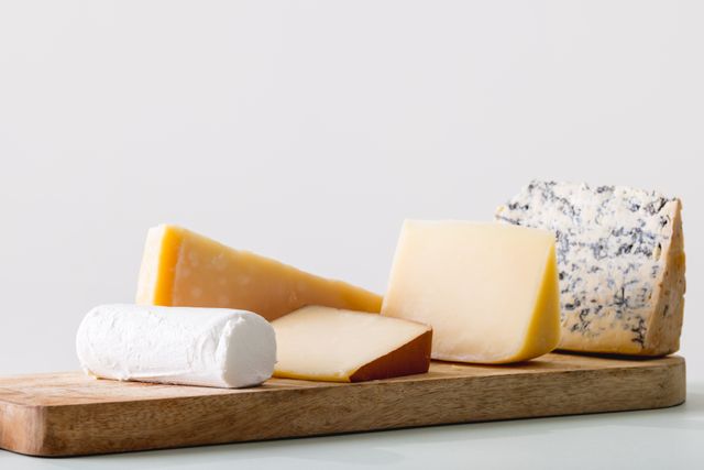 Close-up of various cheese on wooden board against white background with copy space. unaltered, food and dairy product.