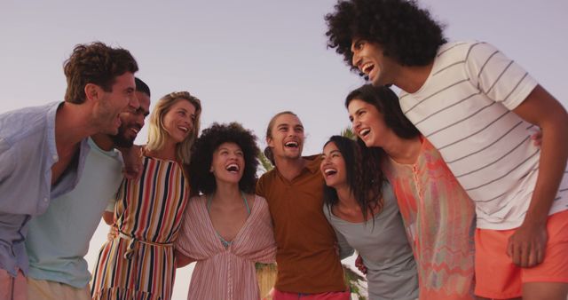 Happy diverse group of friends standing on beach with arms around each other, laughing. Summer, free time, friendship, party, celebration and vacations.