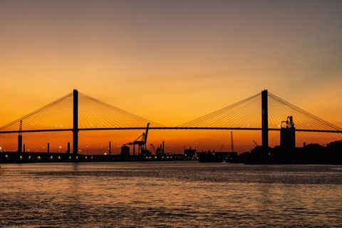 Golden Sunset Over Cable-Stayed Bridge with Industrial Harbor and River Reflections