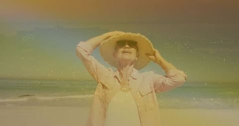 Senior woman enjoying sunny beach day wearing straw hat and sunglasses