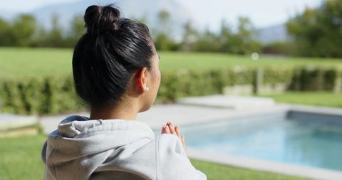 Woman Meditating by Backyard Pool in Serene Outdoor Setting