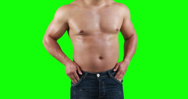 Muscular shirtless man in jeans standing confidently against green screen background. Useful for fitness advertisements, health and wellness promotions, or body positivity campaigns. Versatile for graphic design projects, allowing easy background replacement.