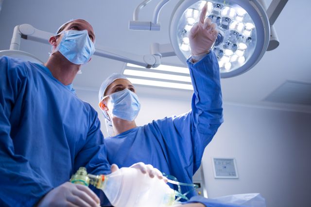 Surgeons in an operating room discussing a procedure. Ideal for use in healthcare, medical training, hospital advertisements, and articles on surgical procedures.