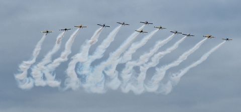 Formation of Aerobatic Planes Creating Smoke Trails Against Cloudy Sky