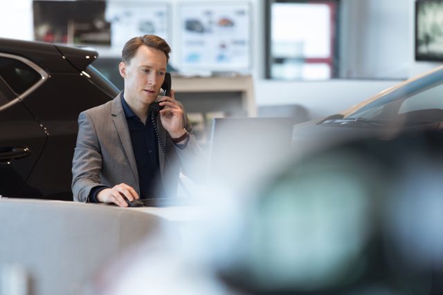 Car salesperson talking on landline phone while working in showroom
