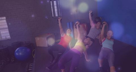 Group strength training: four adults holding dumbbells while bridging on mat in gym studio