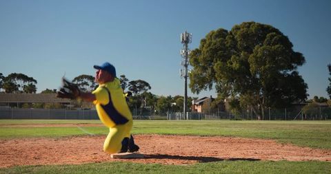Kneeling baseball player reaching with glove for catch on sunlit infield