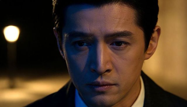 Gazing asian man in suit at night with cinematic duotone lighting and moody urban portrait