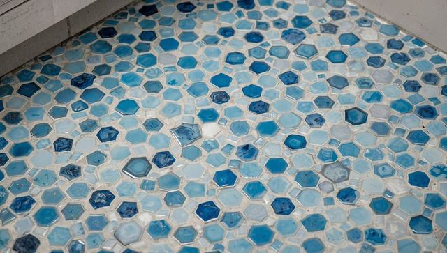Blue hexagonal glass mosaic shower floor featuring aqua teal tiles and light grout