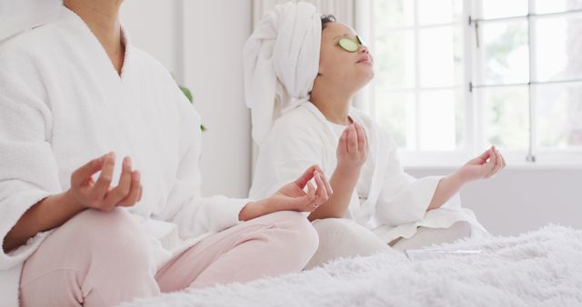 Image of happy asian mother and daughter in robes doing cucumber mask and resting. Family, motherhood, relations and spending quality time together concept digitally generated image.