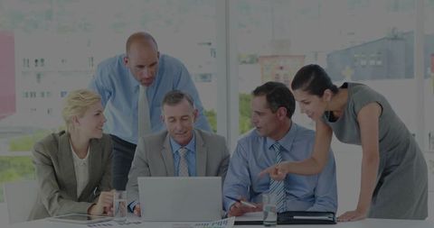 Business team reviewing project data around laptop in modern boardroom with skyline view