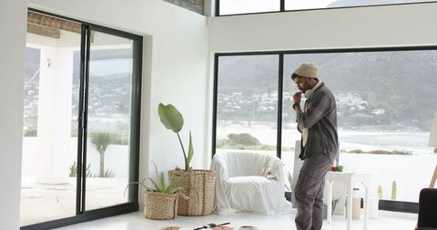 Indian man adjusting jacket in bright coastal minimalist living room with sea view