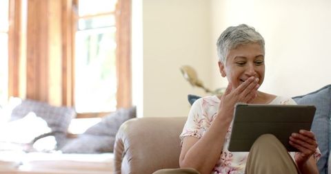 Joyful Senior Woman Laughing Touching Tablet Home Relaxation