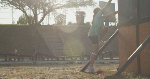 Determined Girl Climbing Obstacle Course Wall at Bootcamp