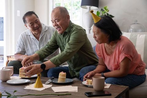 Chinese friends celebrating birthday at home sharing cake and laughter in cozy living room
