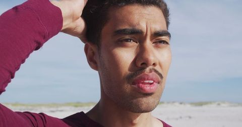 Relaxed hispanic man enjoying sun and wind on beach