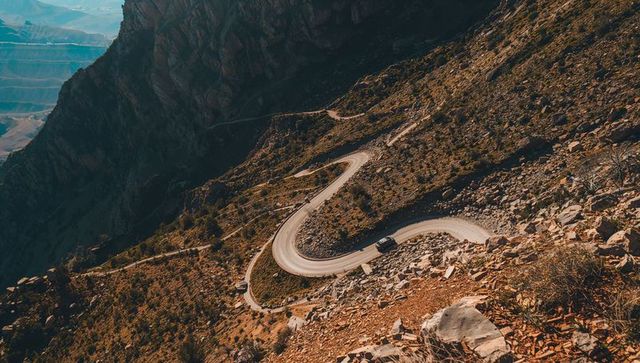 Descending switchback road snaking through arid mountain canyon at golden hour