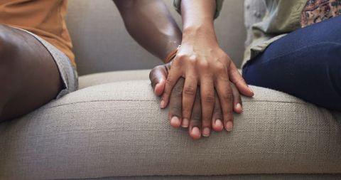 Couple Holding Hands on Sofa, Symbolizing Support and Affection