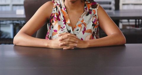 Confident businesswoman sitting at office desk in floral blouse