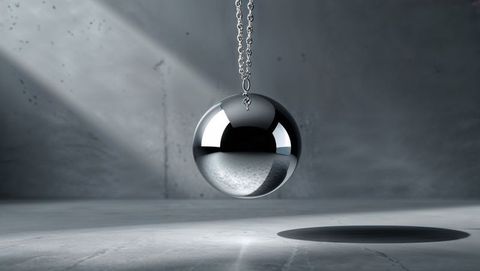 Floating reflective chrome wrecking ball in minimal concrete room