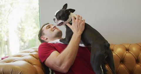 Joyful Man Bonding with Dog on Sofa at Home