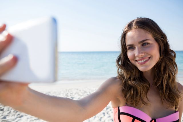 Happy young woman wearing bikini while taking selfie at beach - Download Free Stock Photos Pikwizard.com