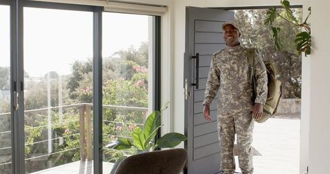 Smiling soldier returning home to bright welcoming house