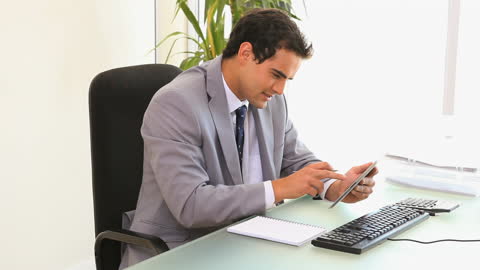 Businessman Using Tablet at Desk in Modern Office Environment