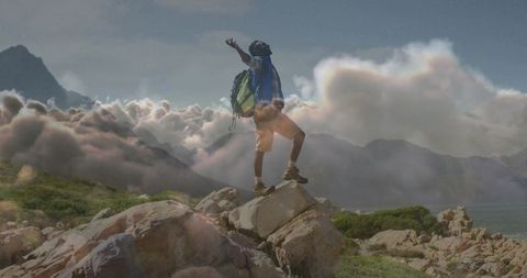 Hiker Triumphing atop Mountain Peak Amidst Stunning Clouds