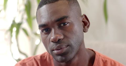 Calm African American man portrait in orange T-shirt looking at camera in natural light