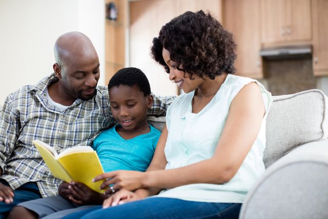 Parents and their son are sitting on a couch in the living room, reading a book together. The scene depicts a warm and loving family moment, emphasizing the importance of education and bonding. This image can be used for articles or advertisements related to family life, parenting tips, educational content, or home living.