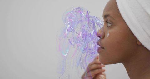 Applying moisturizer at mirror with iridescent beauty swirls, towel-wrapped woman reflecting