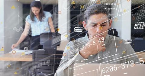 Young analyst analyzing data on laptop with futuristic overlays in open-plan office
