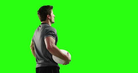 Athlete Holding Rugby Ball with Green Background and Copy Space