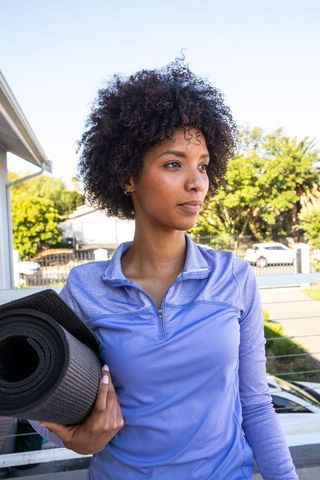 Active African American Woman with Yoga Mat on Balcony