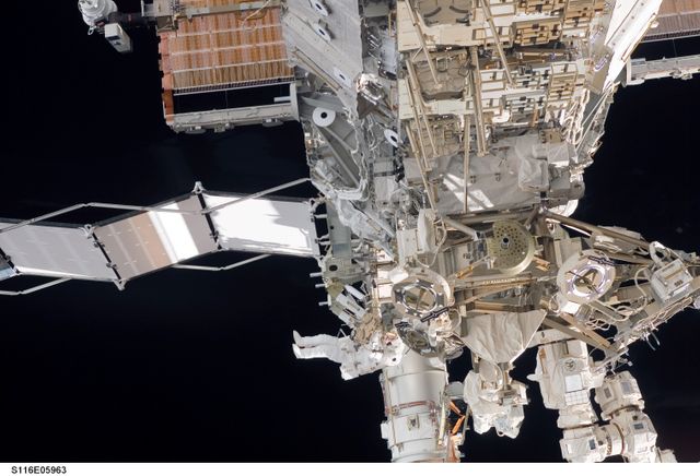 Astronauts participating in extravehicular activity on the International Space Station are shown conducting repairs and construction. This image is useful for educational materials, documentaries about space exploration, and scientific presentations on astronaut missions and space station activities.