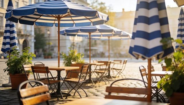 Sunlit bistro terrace with blue striped parasols and wooden tables on cobblestone plaza
