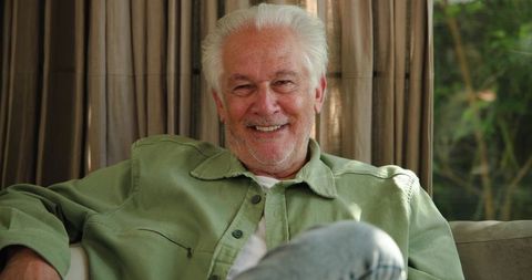 Senior Man Relaxing on Sofa with Gentle Smile in Modern Living Room